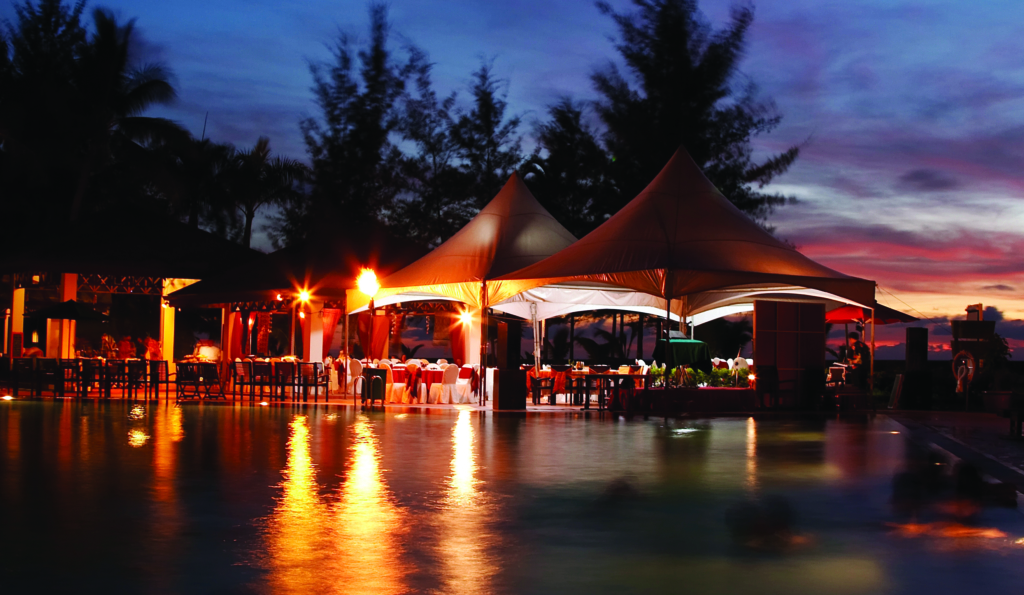 Tables and tents at the pool ready for the reception. The picture was made with a long exposure, thus trees and people figures are blurred.